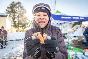 Jess Cerra eating a JoJe bar at a ski event.