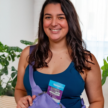 Woman smiling holding Vitassium FastChews Grape packet