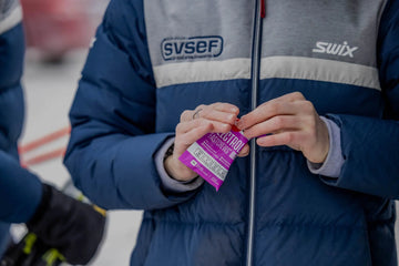 A person in a ski jacket opening a packet of SaltStick Mixed Berry FastChews electrolytes