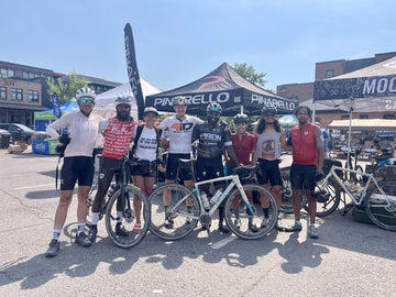 A group of bicycle riders posing in front of event tents.