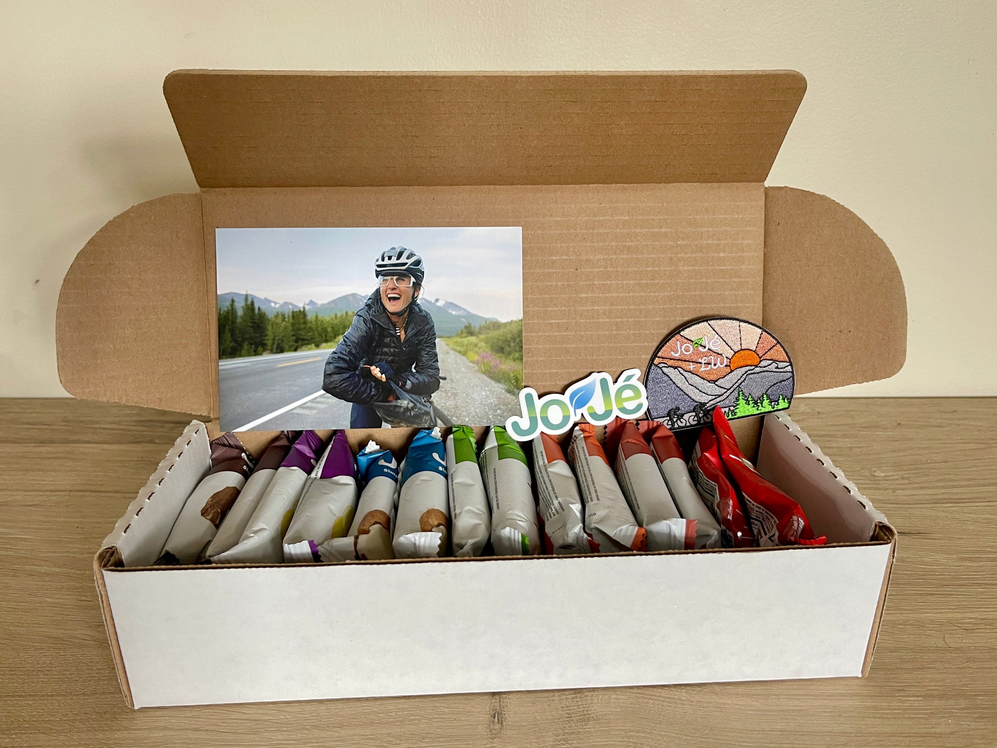 Open box showing the included JoJe Bars, Bonk Breaker Cola Energy Chews, JoJe sticker, Lael postcard and JoJe/Lael patch