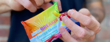 Close up of hands ripping open packet of Rainbow Blast Energy Chews