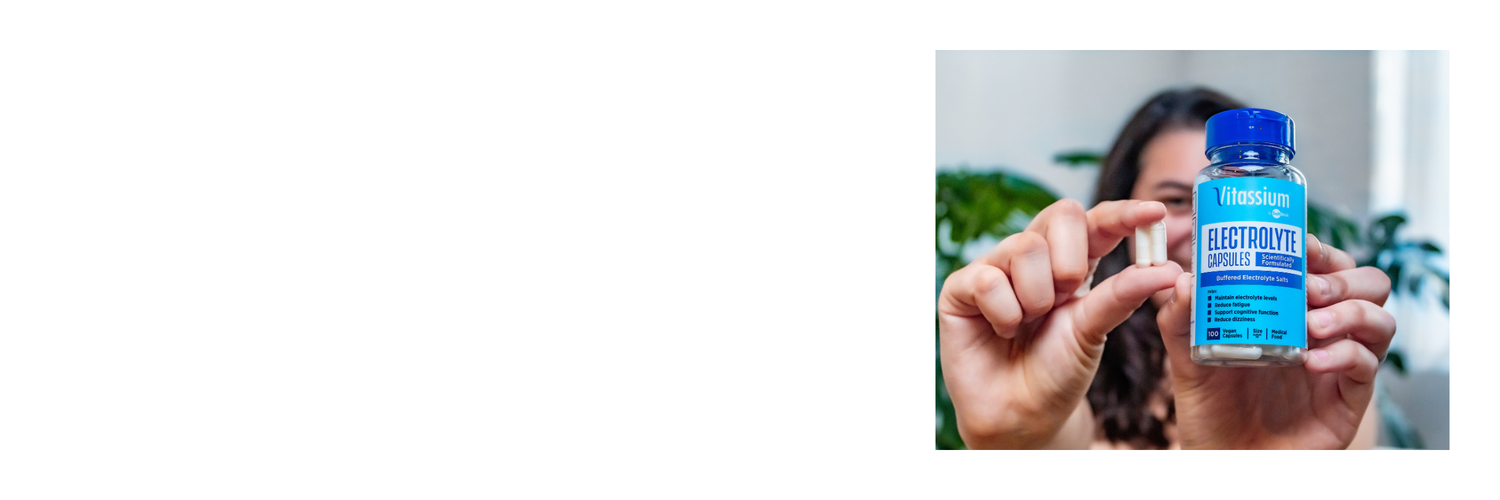 A person holds a bottle of Vitassium Capsules in one hand and two capsules in the other hand. 