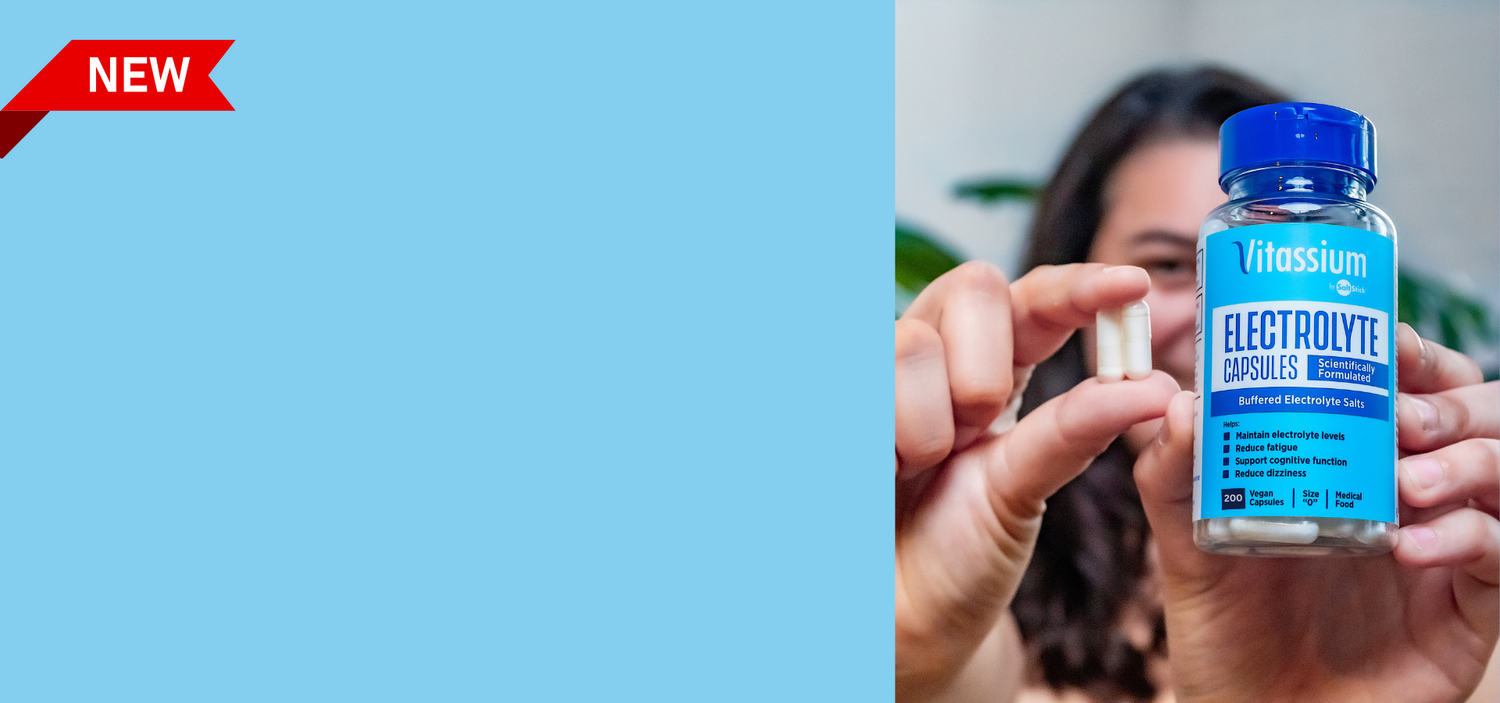 A Vitassium fan holds up a 200ct bottle of Vitassium Capsules in one hand, and two Capsules in the other hand.