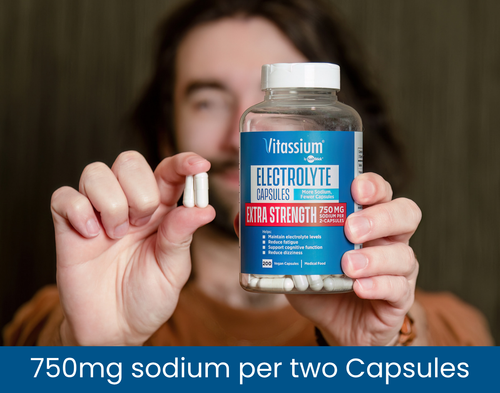 Person holding Vitassium Electrolyte Capsules Extra Strength, 200 vegan capsules with 750 mg sodium per two capsules, alongside two white capsules.