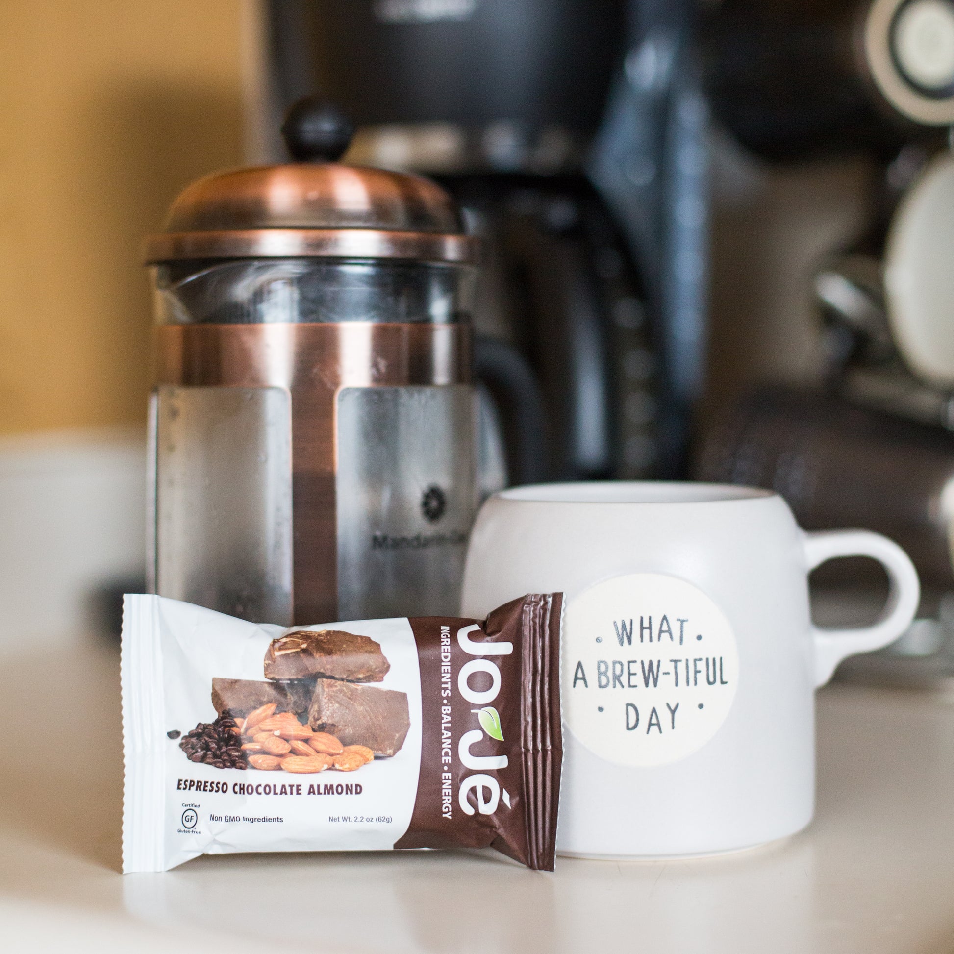 JoJé Espresso Chocolate Almond Bar with a coffee maker and mug